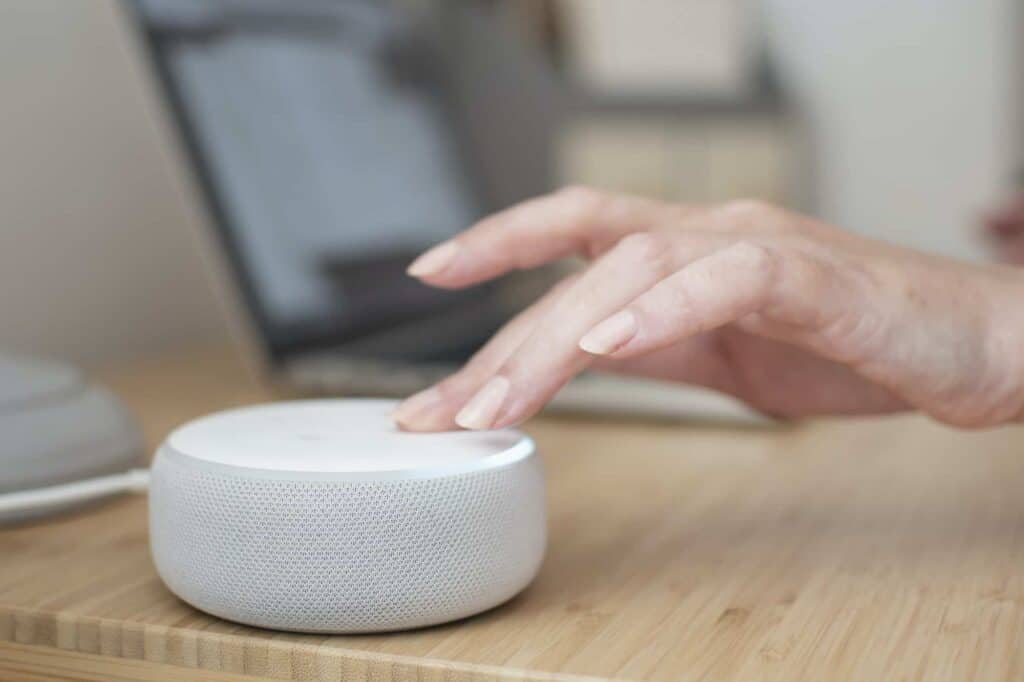 A woman’s hand turns down the volume on an Amazon Alexa device