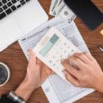 cropped view of man using calculator with tax form and laptop on background