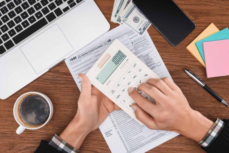 cropped view of man using calculator with tax form and laptop on background