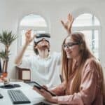 Playful office worker with virtual reality glasses and woman with tablet